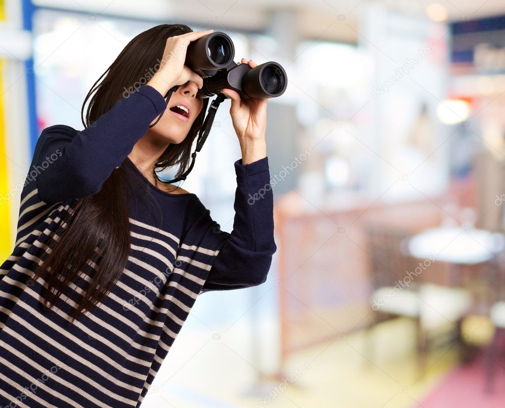Portrait of young girl looking through a binoculars indoor