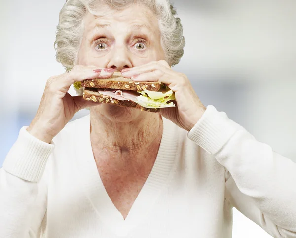 Seniorin isst ein gesundes Sandwich, drinnen — Stockfoto