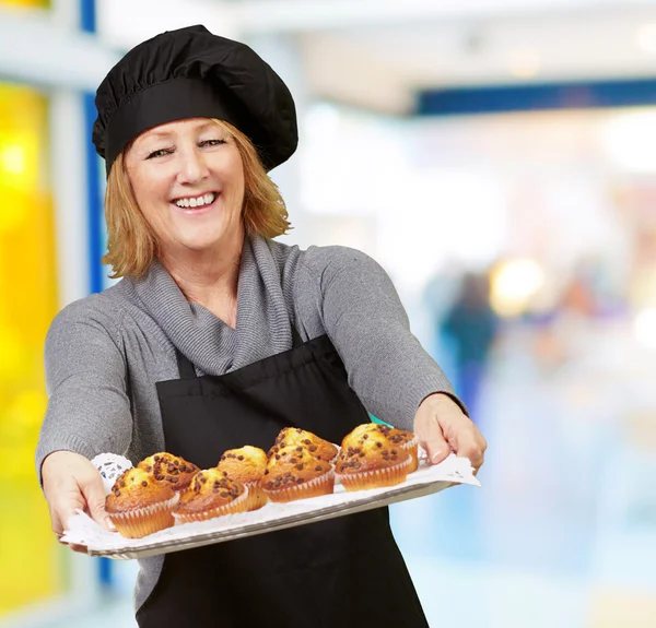Портрет женщины-повара, показывающий поднос с домашними кексами в ресторане — стоковое фото