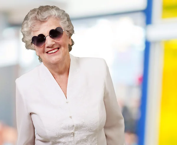 Portrait de femme âgée heureuse portant des lunettes cardiaques à l'intérieur — Photo