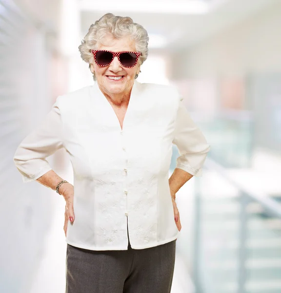 Ritratto di donna anziana che sorride e indossa occhiali da sole a moderatore — Foto Stock