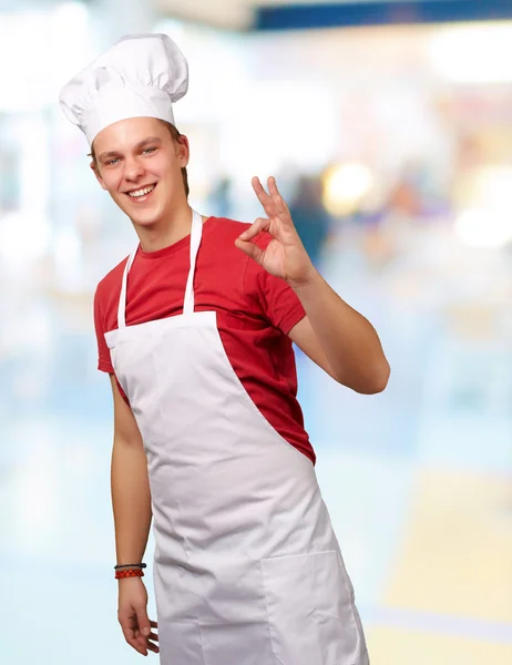 Portret van jonge kok man doen succes symbool binnen — Stockfoto