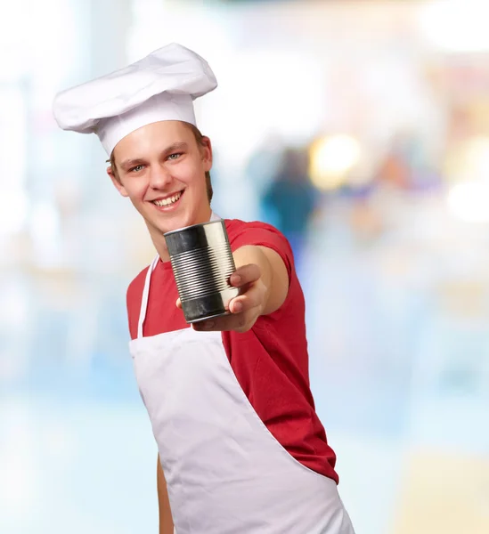 Retrato de jovem cozinheiro segurando uma lata de metal pode interior — Fotografia de Stock