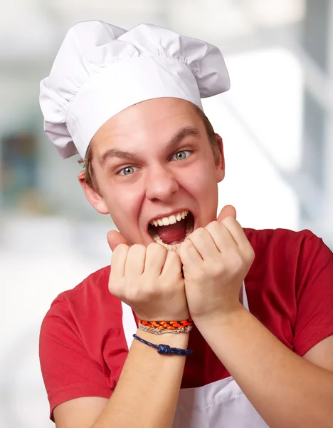 Portrait of young cook man screaming indoor — Stock fotografie