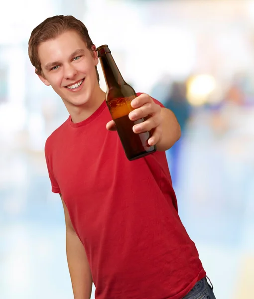 Портрет молодого человека, держащего пиво на абстрактном фоне — стоковое фото