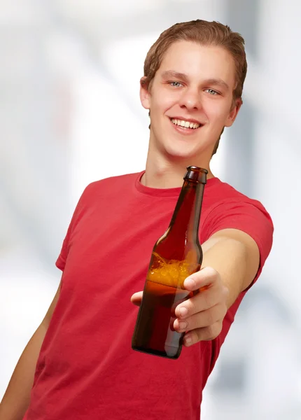 Portrett av en ung mann som holder øl innendørs – stockfoto