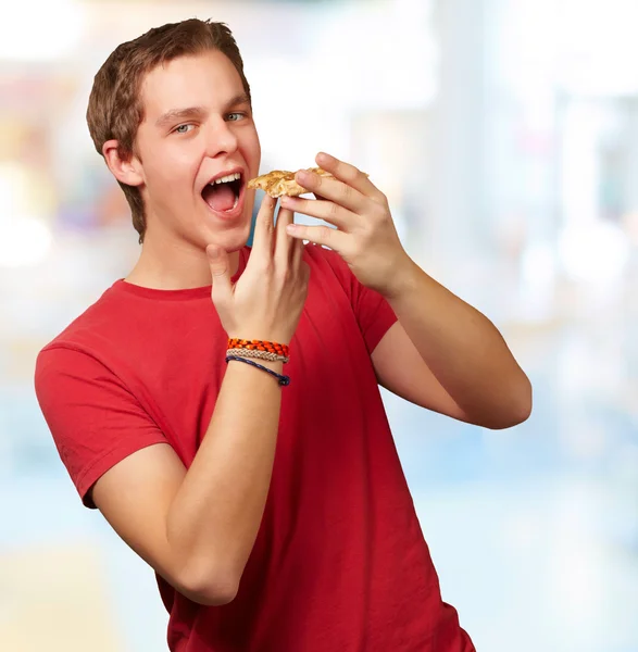 Porträt eines jungen Mannes beim Pizza essen vor abstraktem Hintergrund — Stockfoto