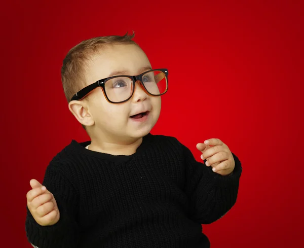 Retrato de criança adorável vestindo óculos e gesticulando sobre vermelho — Fotografia de Stock