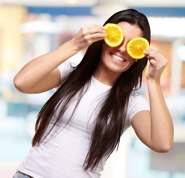 Портрет молодої жінки, що тримає апельсинові скибочки перед очима — стокове фото
