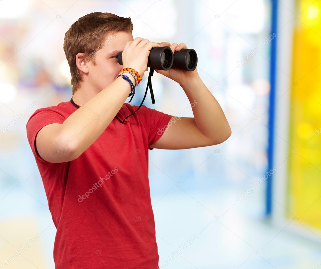Portrait of young man looking through a binoculars indoor