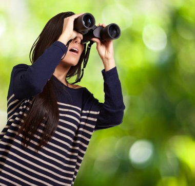 Portrait of young girl looking through a binoculars against a na clipart