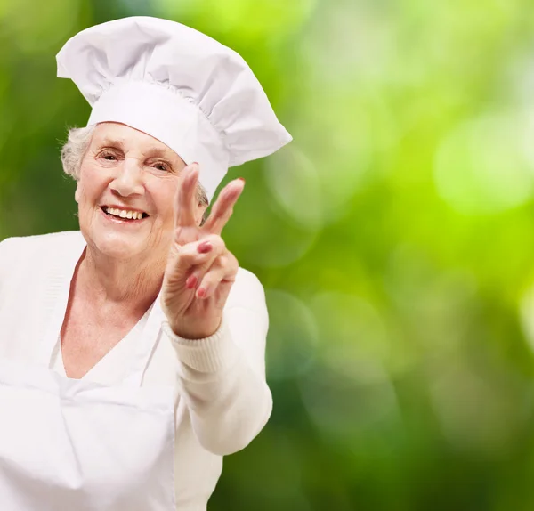 Portret senior kobieta kucharz robi dobry gest przeciwko natur — Zdjęcie stockowe
