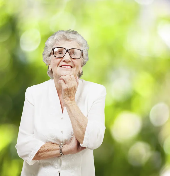 Portrait of senior woman thinking and looking up against a natur — Stock Photo, Image
