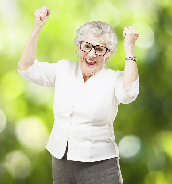 Retrato de una alegre mujer mayor haciendo gestos de victoria contra un — Foto de Stock