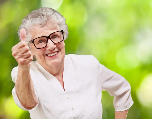 Retrato de mujer mayor adorable haciendo buen gesto contra un n — Foto de Stock