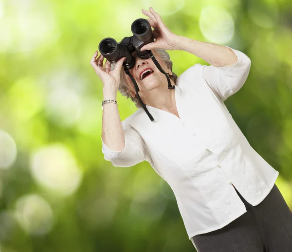 Portrét starší ženy dívá dalekohledem proti — Stock fotografie