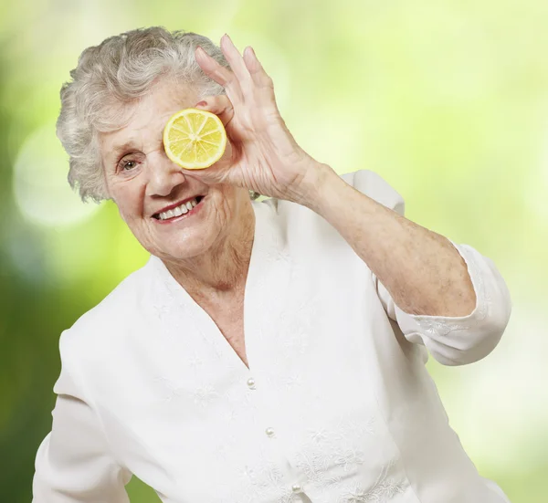 Ritratto di donna anziana con limone davanti agli occhi contro — Foto Stock