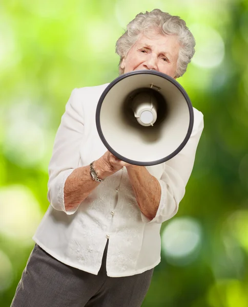 Portrait de femme âgée criant avec mégaphone contre un natu — Photo