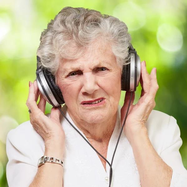 Porträt einer Seniorin, die vor einem Naturbad Musik hört — Stockfoto