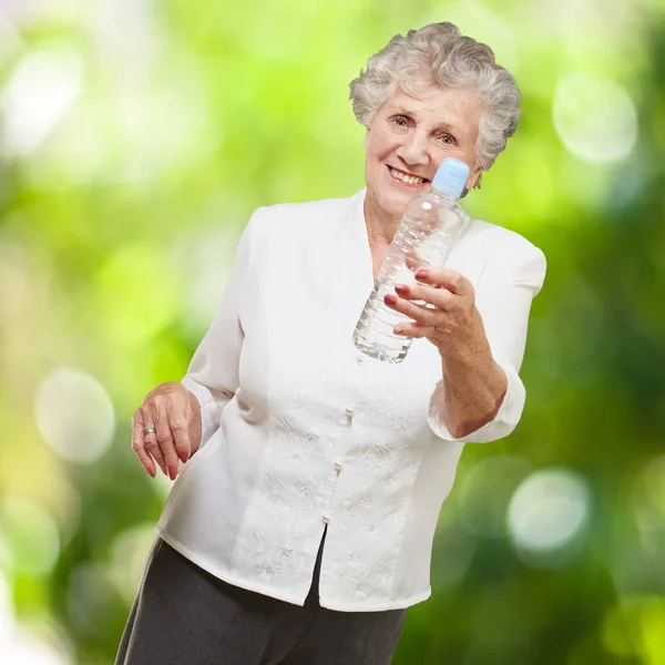 Portrait d'une femme âgée en bonne santé tenant une bouteille d'eau contre — Photo