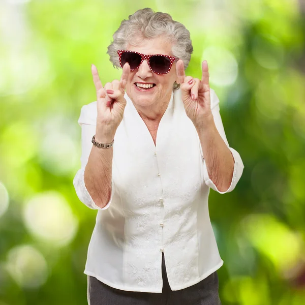 Portret szczęśliwy starszy kobieta robi skały symbol przeciwko nat — Zdjęcie stockowe