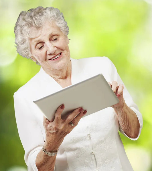 Porträt einer Seniorin, die ein digitales Tablet gegen eine Natur anfasst — Stockfoto