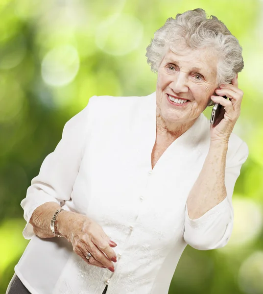 Porträt einer Seniorin, die mit dem Handy gegen den Rücken der Natur spricht — Stockfoto
