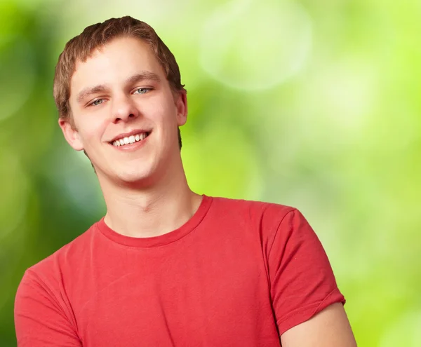 Porträt eines jungen Mannes, der vor einem Hintergrund der Natur lächelt — Stockfoto