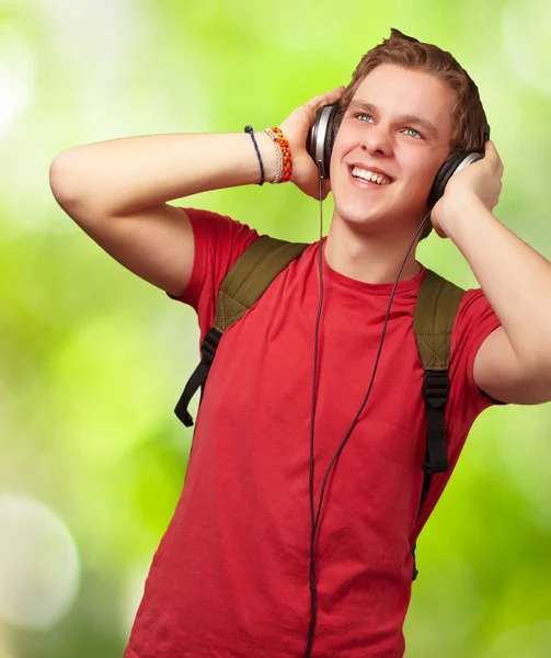 Portrait of cheerful young student listening music with headphon — Stock Photo, Image