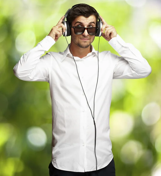 Portrait of young man listening to music using headphones agains — Stock Photo, Image