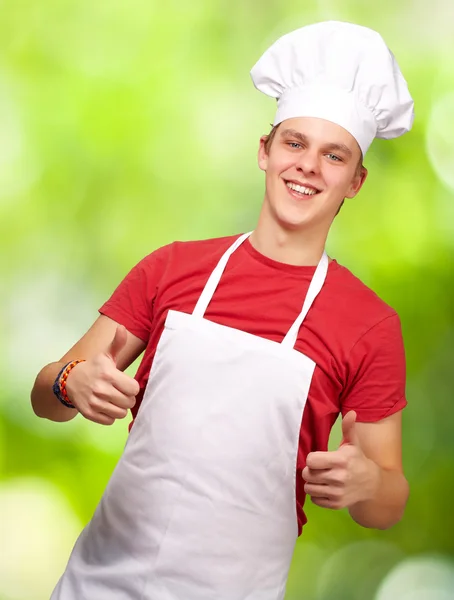 Bir doğaya karşı başarı sembolü yapan genç aşçı erkek portresi — Stok fotoğraf