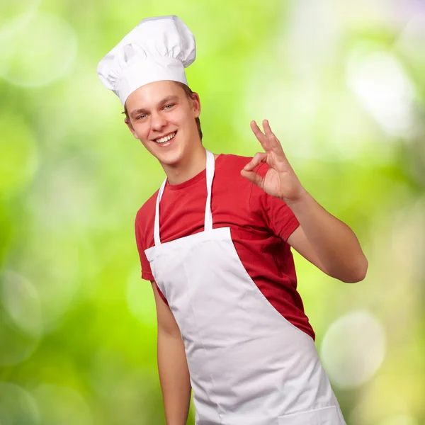 Retrato de jovem cozinheiro fazendo símbolo de sucesso contra uma natureza — Fotografia de Stock