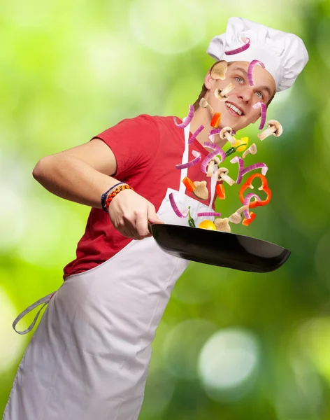 Ritratto di giovane cuoco che cucina verdure contro una natura b — Foto Stock