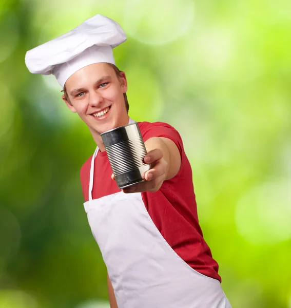 Portrait of young cook man holding a metal tin can against a nat — Stock Photo, Image
