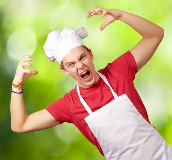 Portrét mladého kuchaře muž nosí zástěru dělat agresivní gestur — Stock fotografie