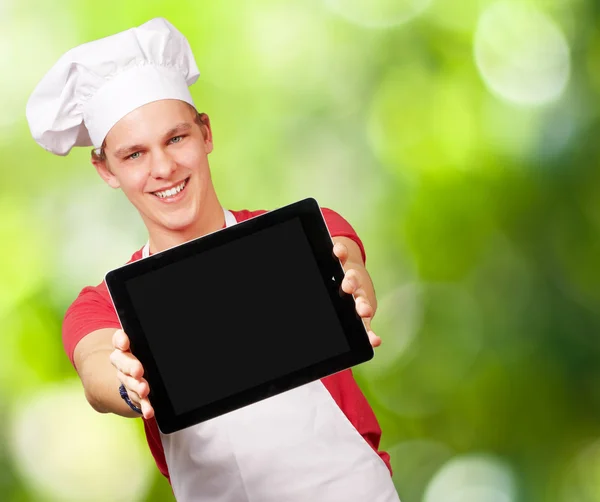 Portrait of young cook man showing a digital tablet against a na — Stock Photo, Image