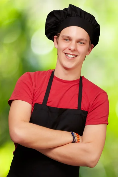 Retrato del joven cocinero vistiendo uniforme y sonriendo contra un —  Fotos de Stock