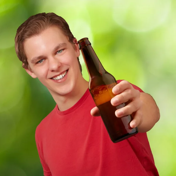 Porträtt av ung man hålla öl mot en natur bakgrund — Stockfoto