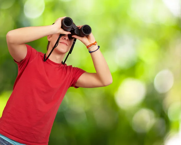 Portrait of young man with binoculars against a nature backgroun — Stock Photo, Image