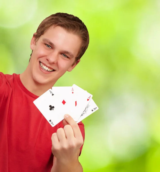 Ritratto di giovane uomo che tiene carte da poker contro un backg natura — Foto Stock