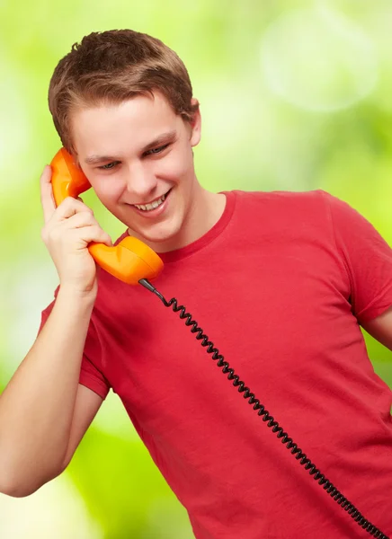Portrait of young man talking on vintage telephone against a nat — Stock Photo, Image
