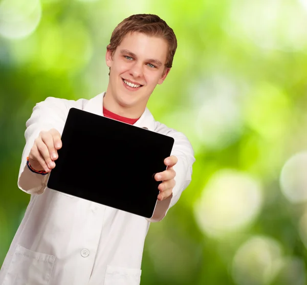 Retrato de un joven mostrando una tableta digital contra una naturaleza ba —  Fotos de Stock