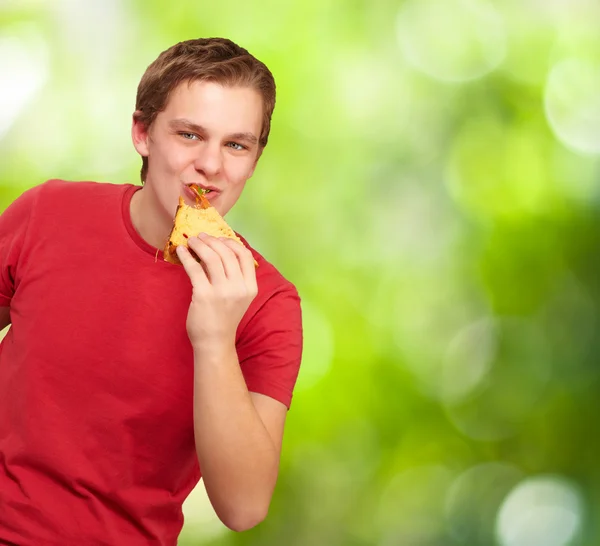 自然を背景に若い男が食べるピザの肖像画 — ストック写真