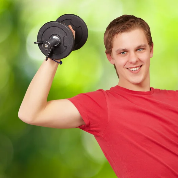 Mladý muž dělá fitness s váhami pozadí přírody — Stock fotografie