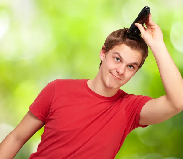 Portrait of young man cutting his hair against a nature backgrou — Stock Photo, Image