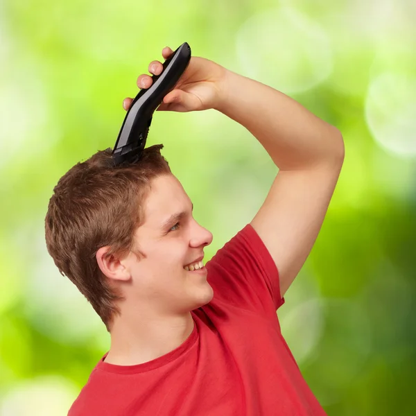 Portrait of young man cutting his hair against a nature backgrou — Stock Photo, Image