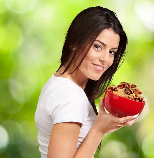 Portrait of young woman holding a cereal bowl against a nature b — Stock Photo, Image