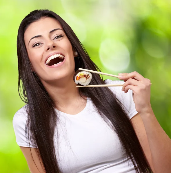 Portrait of young woman holding sushi against a nature backgroun — Stock Photo, Image