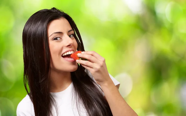 Portrait of young woman eating strawberry against a nature backg — Stock Photo, Image