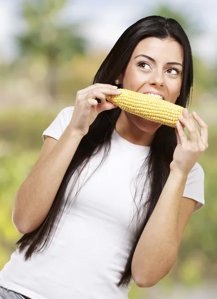 Maissintähkää syövä nainen — kuvapankkivalokuva